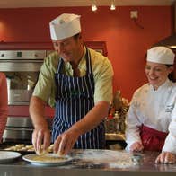 A chef showing two students how to cook in a red kitchen in Ballyknocken, County Wicklow
