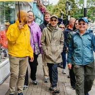 Guide holding an umbrella leading a group of smiling people