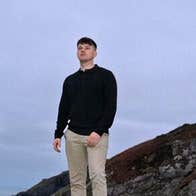 3 men standing apart outdoors with dull sky