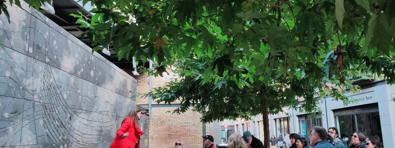 A tour guide speaking to a group of people at an ornate wall on a city street