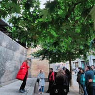 A tour guide speaking to a group of people at an ornate wall on a city street