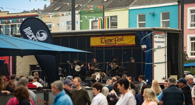 Dungarvan TuneFest 2026, people dancing outside in a town square with trad band playing on small stage.