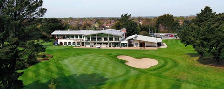 The clubhouse from a distance and a height with a sand dune in the foreground of the picture