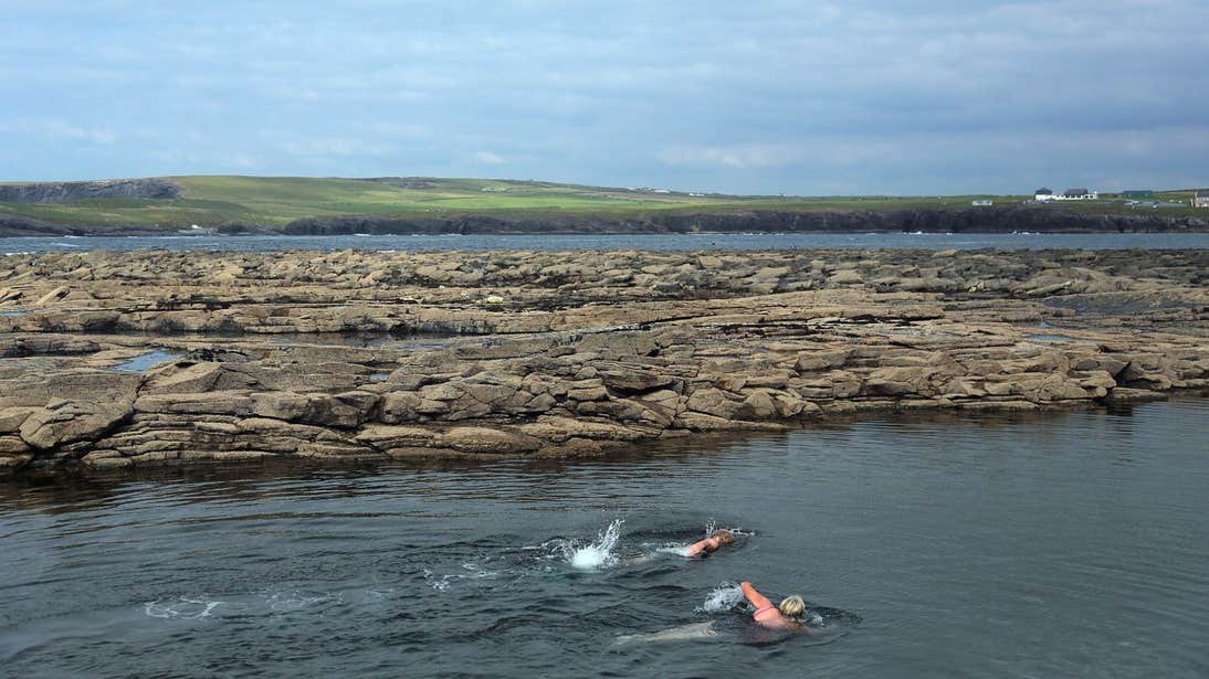 Two people swimming in Kilkee Pollock Holes in County Clare