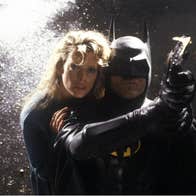 Batman is pointing a grapple-gun. A blonde woman is behind him.