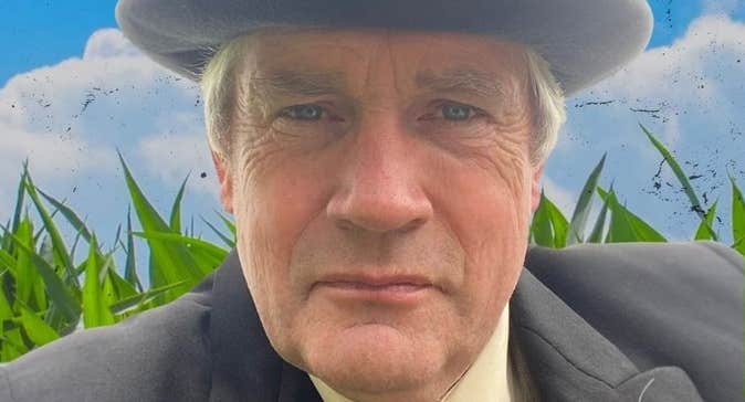 A man in a grey hat and jacket looking intent.
