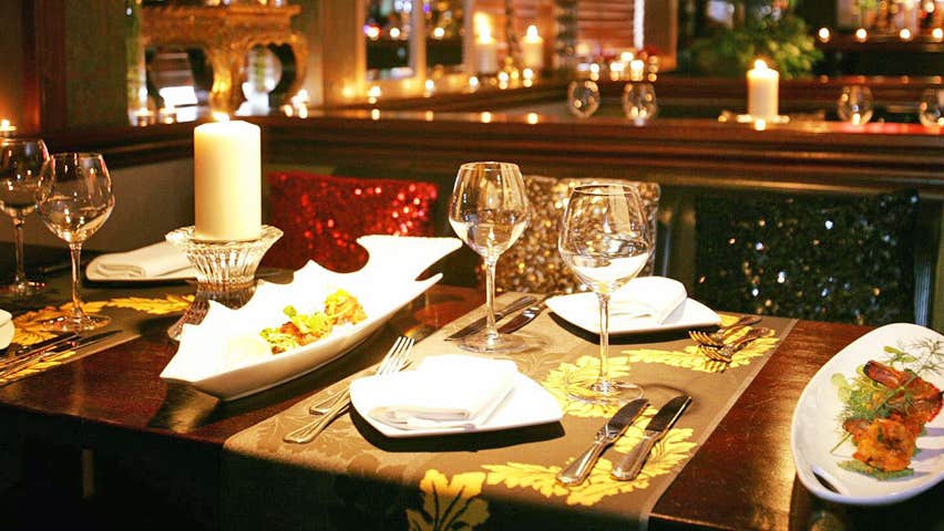 A table set for four in an Indian restaurant with a lit candle on the table and starter dishes to the side