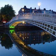 A bridge spanning a river in a city at dusk