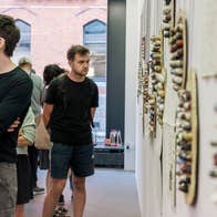 A man stands in a Gallery looking at art on the wall