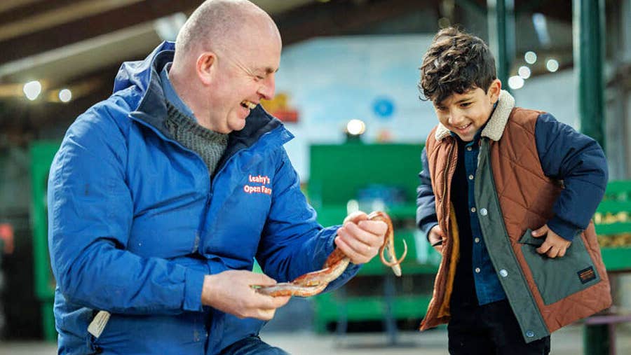 Leahy's Open Farm man laughing while showing a snake to a boy
