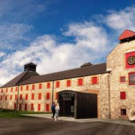 A large building with exterior walls of brick and a replica of a whiskey still outside