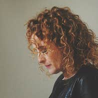 Side view of a woman with curly hair, looking downwards.