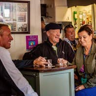 Group sitting in a pub at a tall table with empty shot glasses in front of them