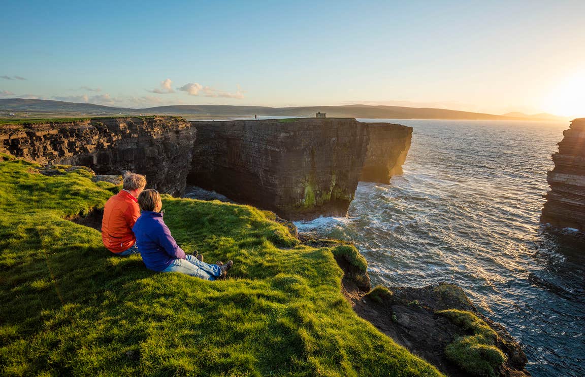 A couple watching the sunset at Downpatrick Head, Co. Mayo