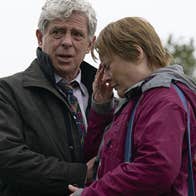 A upset woman being comforted by a man outdoors.