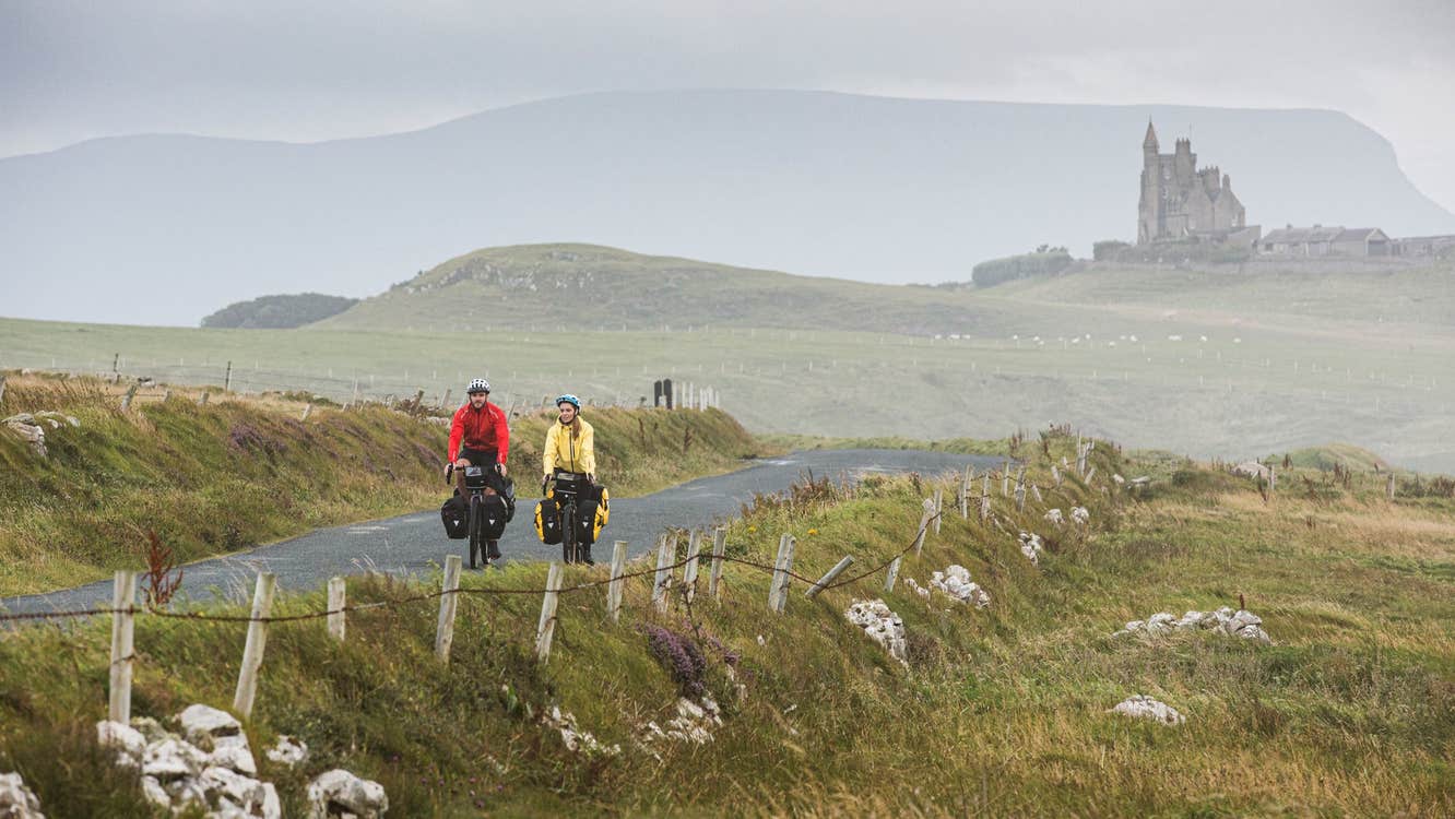 Two cyclists on a country road in County Sligo with Classiebawn Castle in the background