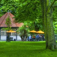Exterior of a tea room with an outside seating set on parkland surrounded by trees