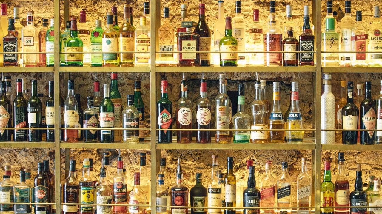 Full shelves of different brands of spirits behind a bar