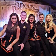 Five Irish dancers sit on a stage to pose for a photograph