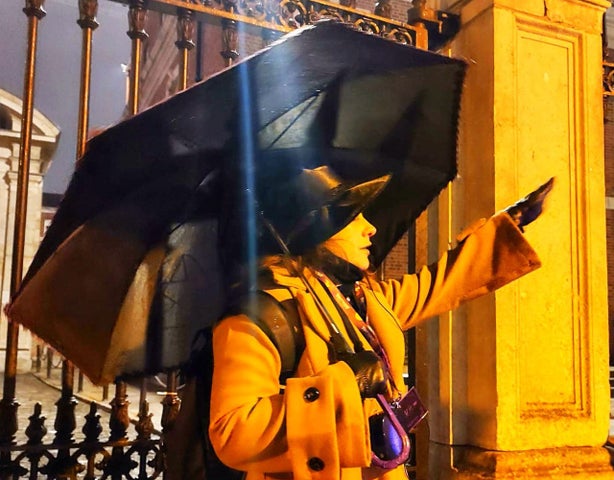 A woman dressed dramatically with an umbrella giving a tour