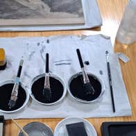 Japanese Water-Based Woodblock Printing (Mokuhanga), art materials for printing laid out on a table including pots of dark ink & brushes