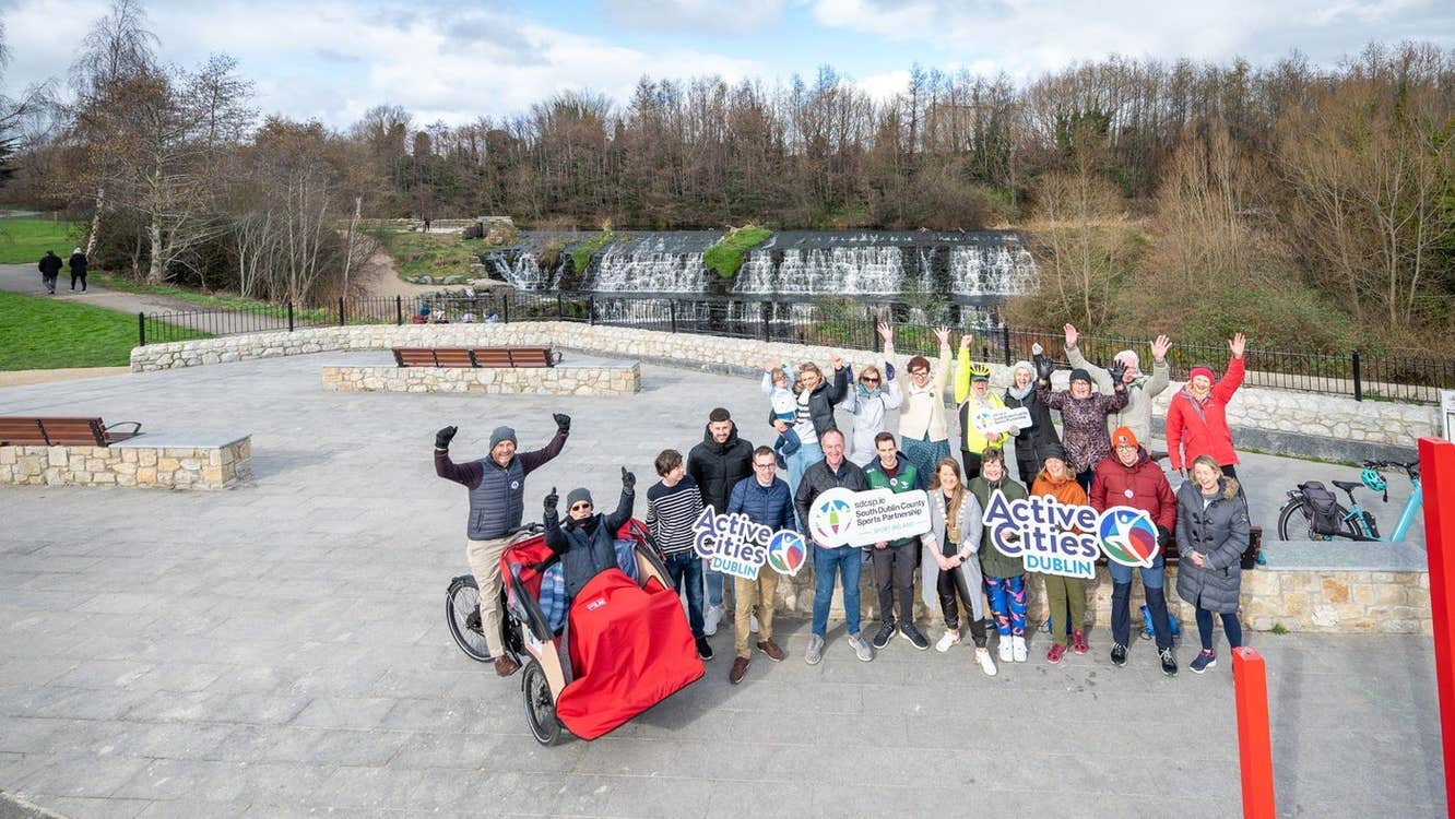 A group of people posing with trishaws and signs promoting cycling
