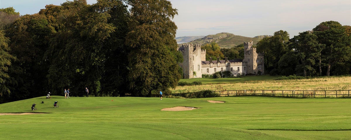 Golfers on a golf course with a castle the background