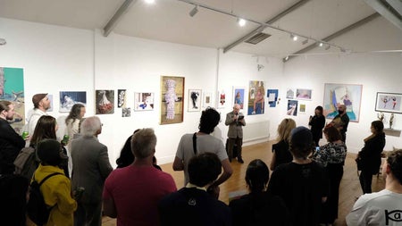 Person giving a talk to a group of people standing in an exhibition room