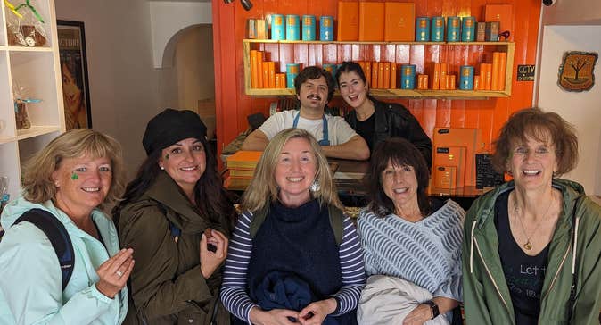 Group of people smiling for a picture with a shelf displaying chocolate and an orange wall in the background