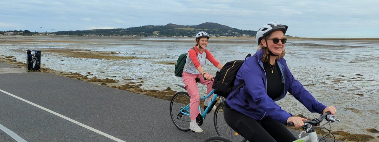 Two ladies on hybrid bikes cycling along the coast