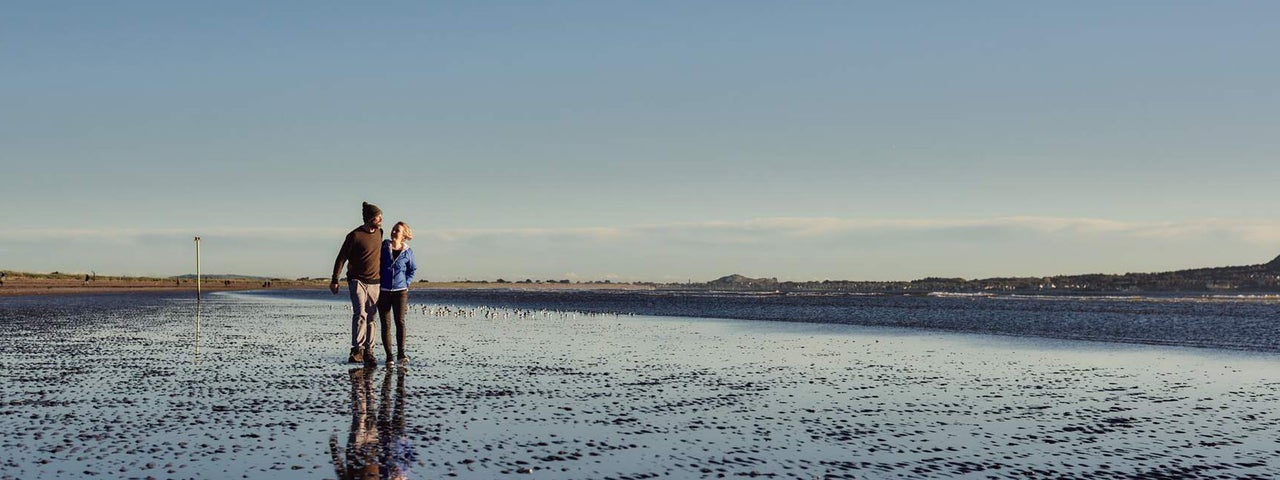 Couple walking on the beach at Bull Island, Dublin City, County Dublin