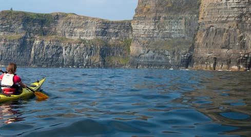 A person kayaking by the Cliffs of Moher in County Clare