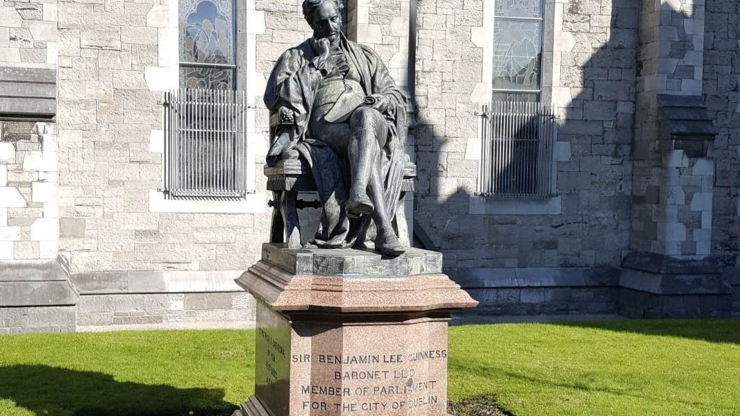 A large statue of a seated man on a plinth with church in the background.