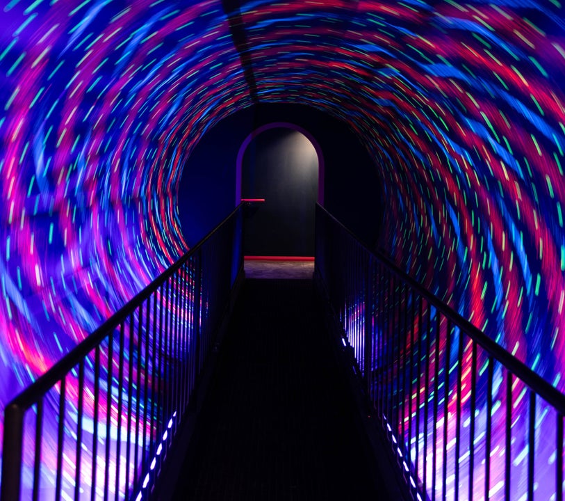 A dark walkway surrounded by a revolving tunnel of lights