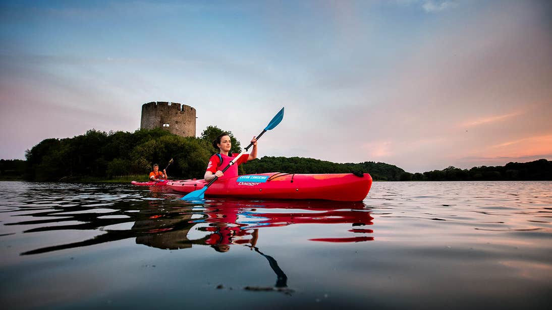 Two people kayaking on Lough Oughter in Cavan in front of a castle