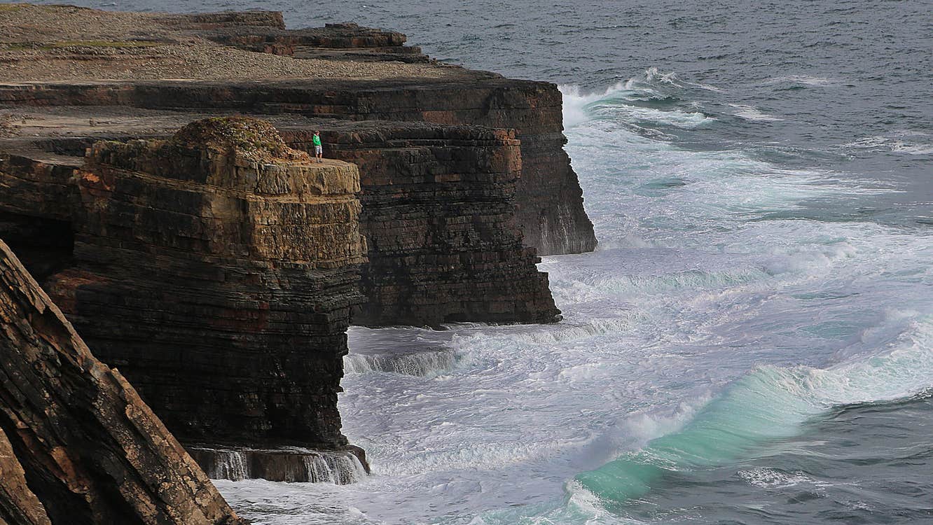 An aerial view of a man standing on a sea cliff at Loop Head Peninsula