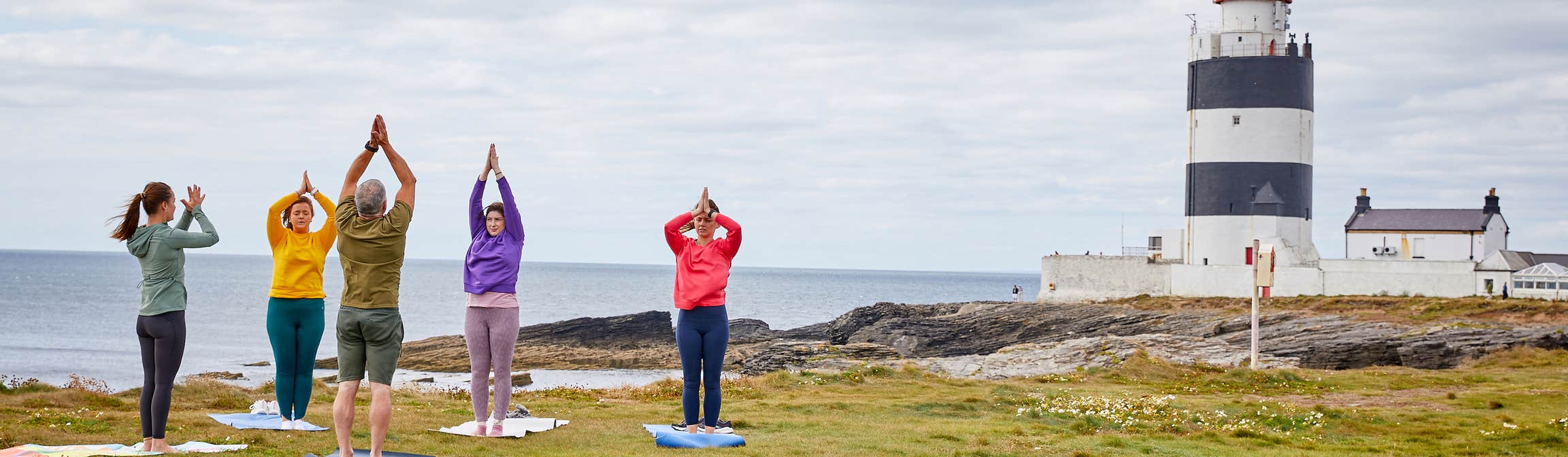 People doing yoga in front of Hook Head Lighthouse.