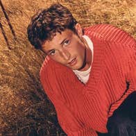 A young man in orange jumper in a field of brown long grass