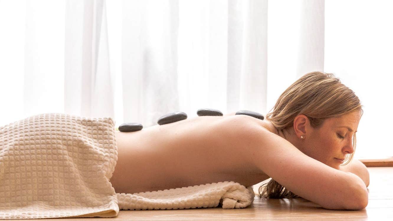 A lady lying on her stomach with hot stones on her back