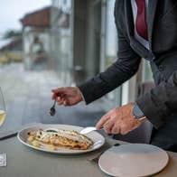 A fillet of grilled fish is being served with a glass of white wine