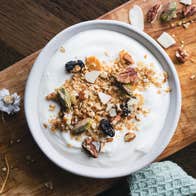 A bowl of creamy yoghurt topped with crunchy granola and dried fruits