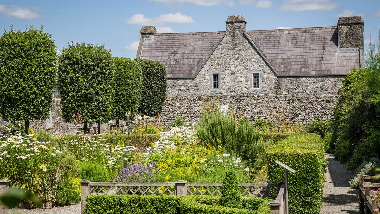 Exterior of a large stone bricked house overlooking a garden