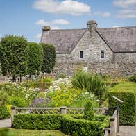 Exterior of a large stone bricked house overlooking a garden