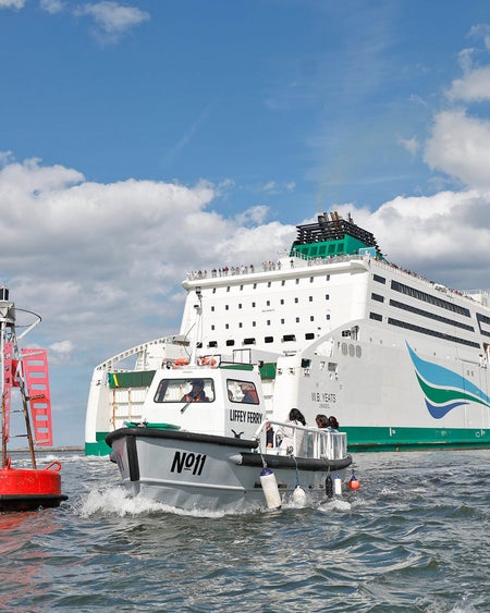 The Old Liffey Ferry number eleven near a large cruise ship