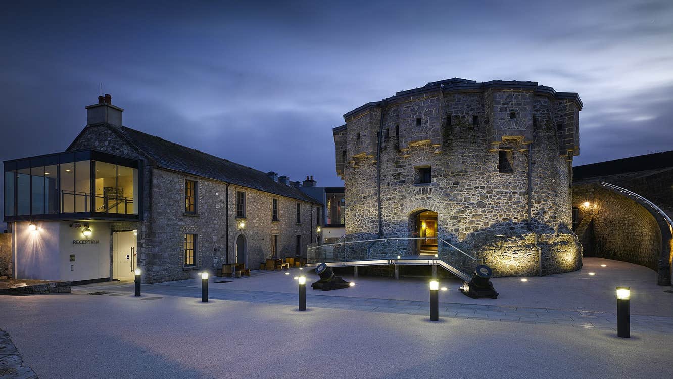 Castle at night time with pillar lights along the footpath in front