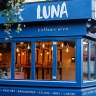 Exterior of café with several long narrow windows with a hanging basket of plants