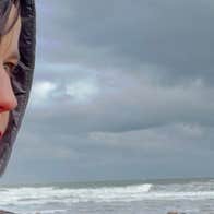 A woman stands in front of a grey sky