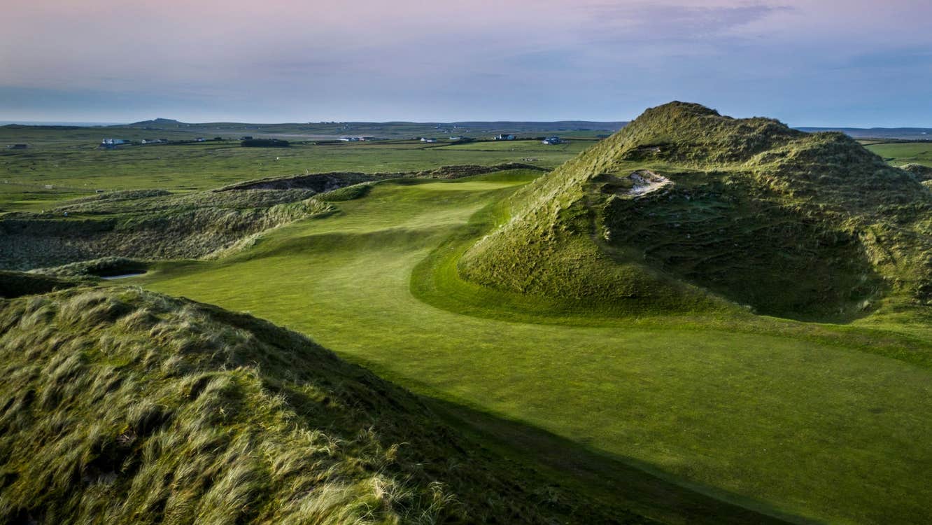 Golf course and bunker with a blue and pink sky in the background