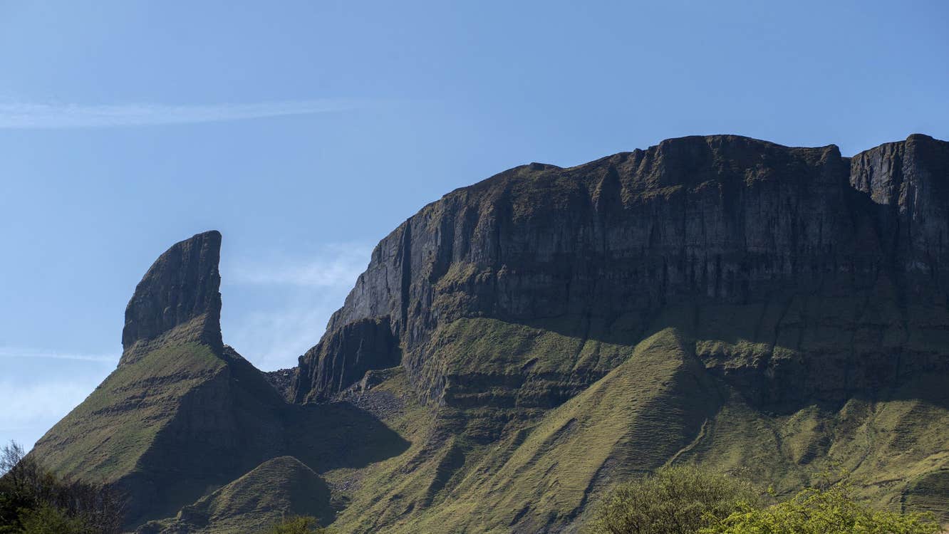 A view of a large rocky tower beside a mountain ridge