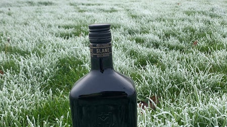 A bottle of whiskey on foggy dew grass with a castle in the background